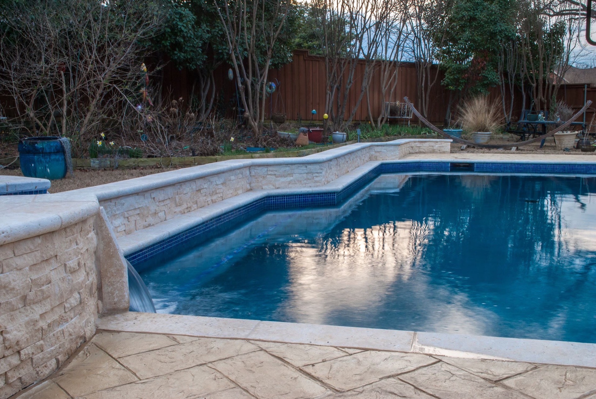 New stone coping, raised wall, and stamped deck on a remodeled North Texas pool